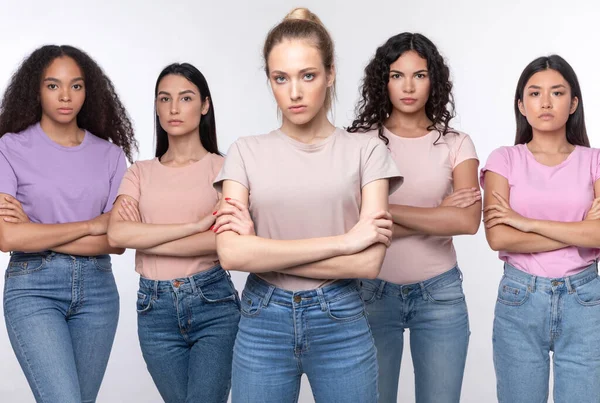 Dispiaciuto donne miste in piedi attraversando le mani su sfondo bianco — Foto Stock