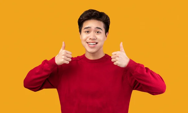 Счастливый азиатский парень, показывающий пальцами вверх и улыбающийся — стоковое фото