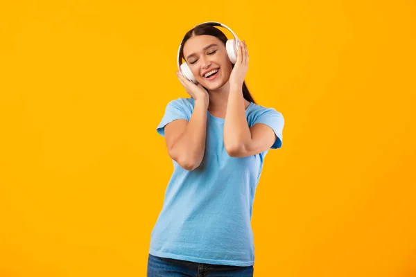 Dame souriante appréciant la musique avec casque et danse — Photo