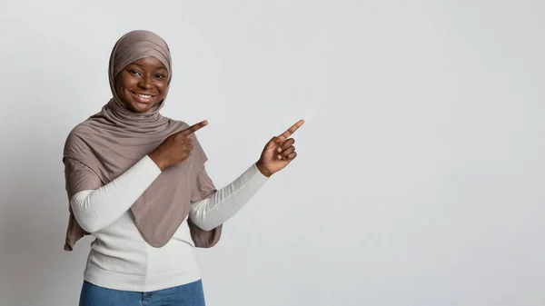 Look There. Black muslim lady in hijab pointing away with two hands — Stock Photo, Image