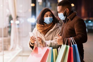 Alışveriş merkezinin yakınında maske takan siyah bir çiftin portresi.