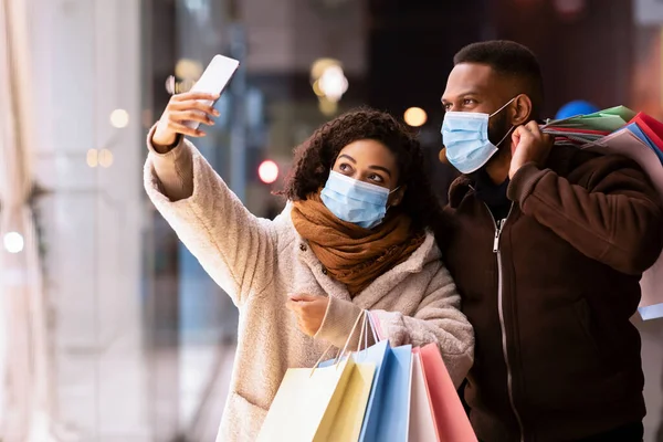 Negro pareja en máscaras tomando selfie después de ir de compras —  Fotos de Stock