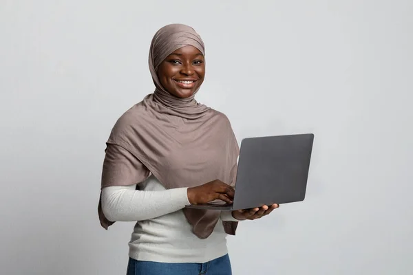 Online oktatás. Portré mosolygós fekete muszlim hölgy fejkendővel gazdaság laptop — Stock Fotó