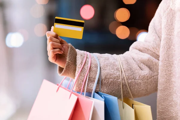 Oigenkännlig svart dam som innehar kreditkort och shoppingväskor — Stockfoto