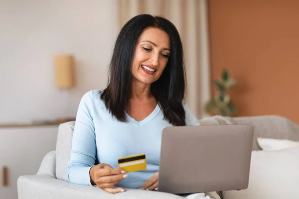 Жінка робить покупки за допомогою ноутбука тримає картку — стокове фото