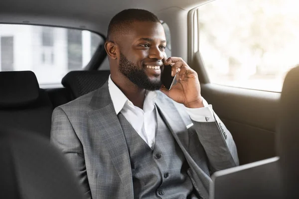 Boldog fekete üzletember beszél mobilon autóban — Stock Fotó