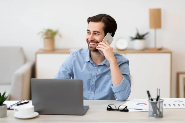 Hombre de negocios alegre hablando por teléfono en la oficina sentado en el lugar de trabajo — Foto de Stock