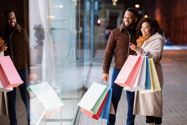 Happy black couple with shopping bags looking at mall window — Stock Photo, Image