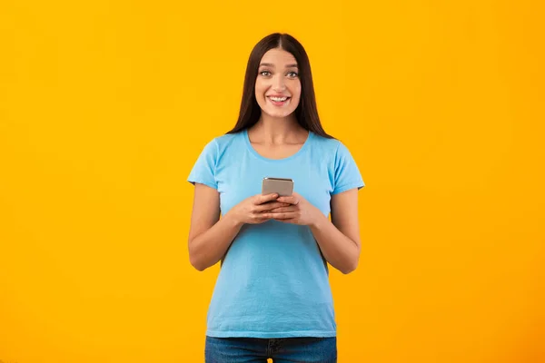 Glimlachende jonge vrouw met behulp van haar mobiele telefoon in de studio — Stockfoto