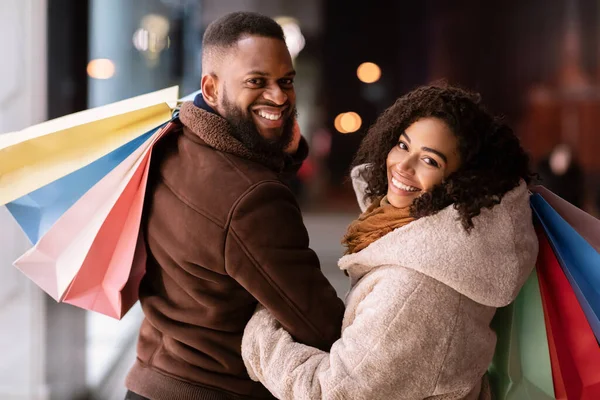 Portrait of happy black couple looking back with shopping bags — Stock Photo, Image