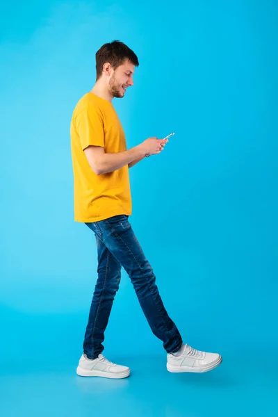 Happy guy met behulp van zijn mobiele telefoon in de studio, volledige lengte — Stockfoto