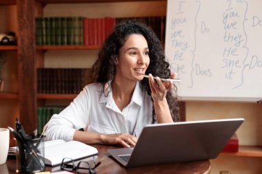 Cep telefonu ve bilgisayarında ses asistanı kullanan genç bayan.