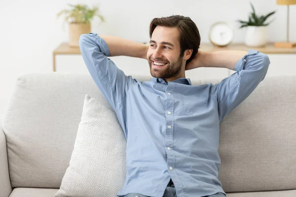 Glücklich entspannter Mann sitzt am Wochenende zu Hause auf Sofa — Stockfoto