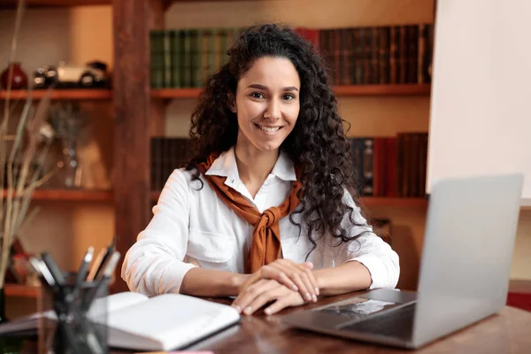 Selbstbewusste Frau posiert am Schreibtisch mit Laptop — Stockfoto