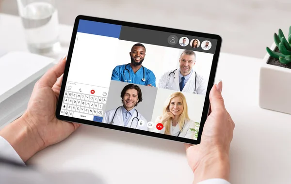 Лікарі онлайн зустрічаються через відео дзвінок на планшет в приміщенні — стокове фото