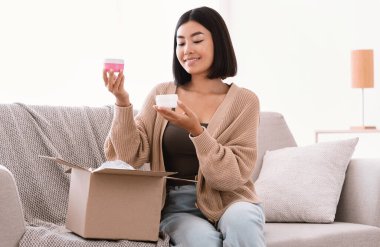 Güzel kutulu paketleri açan mutlu Asyalı kadın.