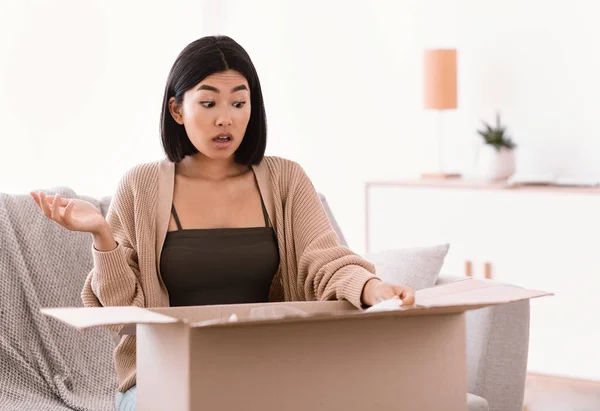 Gefrustreerde aziatische vrouw uitpakken verkeerde pakket, levering fout — Stockfoto