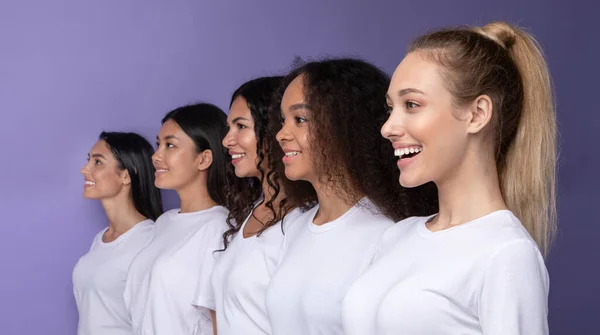 Fünf lächelnde, vielseitige Frauen, die auf lila Hintergrund in Reihe stehen — Stockfoto