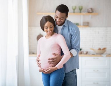 Beklenen Afro-Amerikan kadın ve mutlu erkek arkadaşı evlerinin penceresinin önünde kucaklaşıyorlar.