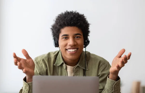 Concepto de educación o comunicación en línea. Sonriente adolescente negro en auriculares hablando con su tutor universitario en la web —  Fotos de Stock