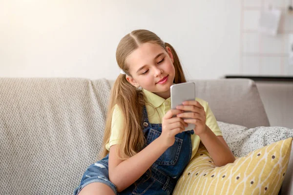 Meisje met behulp van haar smartphone rusten op de bank — Stockfoto
