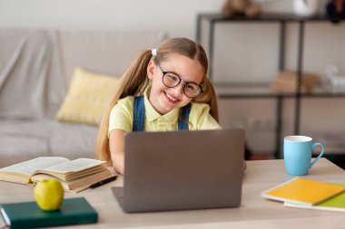 Masada oturan kız, e-öğrenim için dizüstü bilgisayar kullanıyor