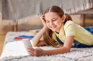 Cep telefonunu evde yerde kullanan bir kız.