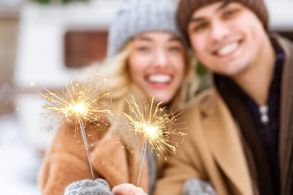 Brennende Wunderkerzen in den Händen eines jungen romantischen Winterpärchens im Freien — Stockfoto