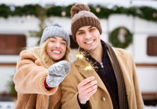 Holidays Celebration. Cheerful Young Couple With Sparklers In Hands Posing Outdoors