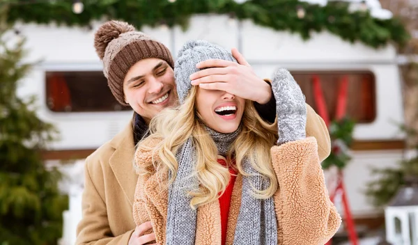 Romântico cara cobrindo os olhos de namorada durante a data ao ar livre no acampamento de inverno — Fotografia de Stock