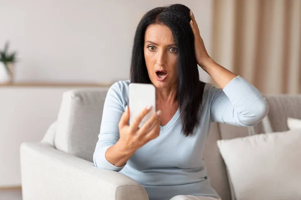 Здивована шокована зріла жінка за допомогою мобільного телефону — стокове фото