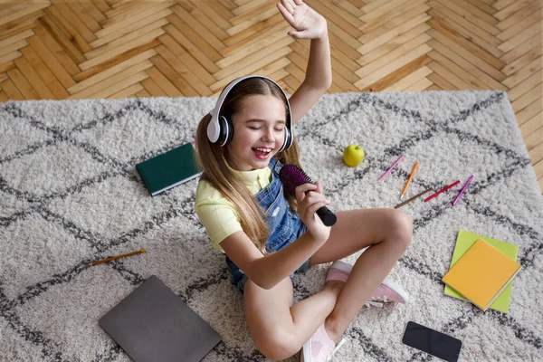 Flicka i headset lyssnar på musik och sjunger i pensel — Stockfoto