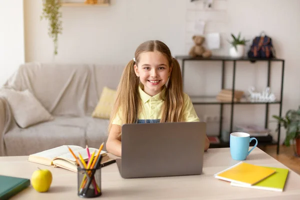 Дівчина сидить за столом, використовуючи ноутбук для електронного навчання — стокове фото