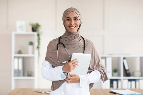 Feliz doctora en hijab posando con tableta digital —  Fotos de Stock