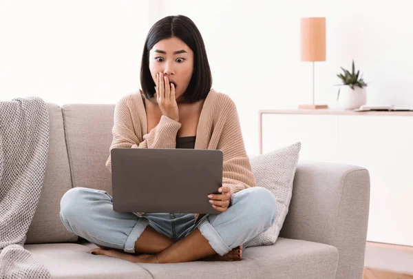 Überrascht asiatisch dame sitting auf couch, using laptop — Stockfoto