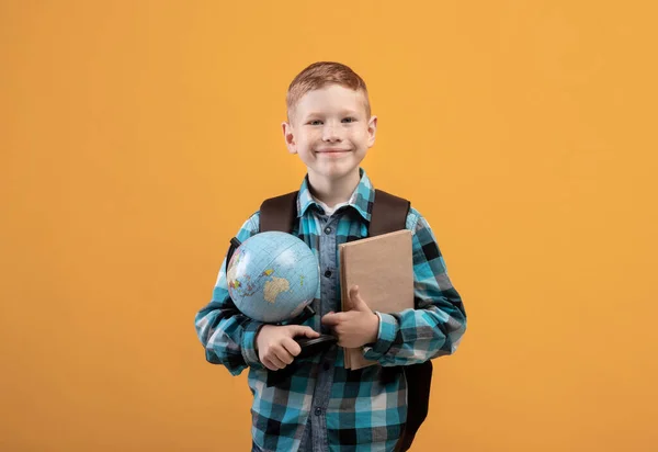 Pozytywny uczeń z plecakiem z kupą książek i globusem — Zdjęcie stockowe