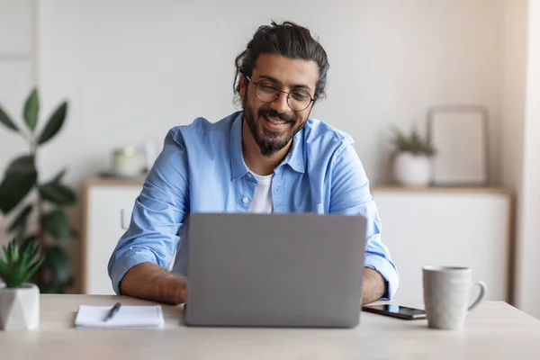 Frilansarbete. Glad Millennial Indian Man arbetar på datorn på inrikesministeriet — Stockfoto