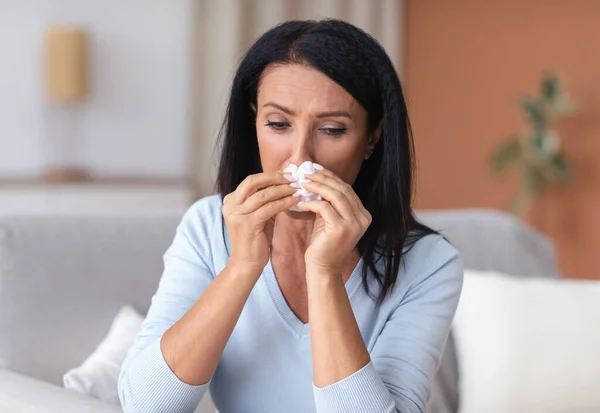 Mujer madura enferma estornudando y llorando, sosteniendo papel tisú — Foto de Stock