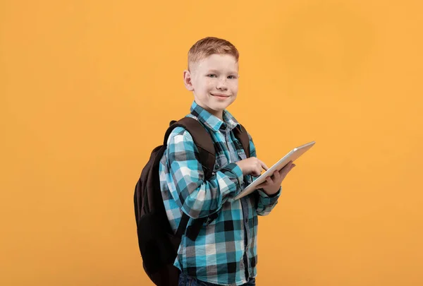Sarı tablet kullanan neşeli okul çocuğu. — Stok fotoğraf