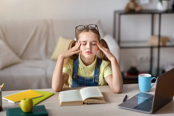 Chica cansada masaje templos sentado en el escritorio con el ordenador portátil — Foto de Stock