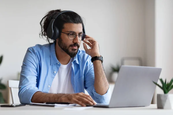 Enseñanza a distancia. Hombre occidental en los auriculares que estudian en línea con el ordenador portátil en casa —  Fotos de Stock