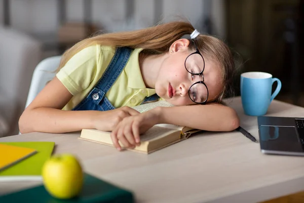 Cansada menina da escola em óculos dormindo à mesa com livro — Fotografia de Stock