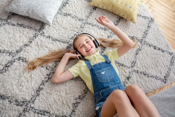 Tonårstjej som ligger på golvmattan och lyssnar på musik — Stockfoto