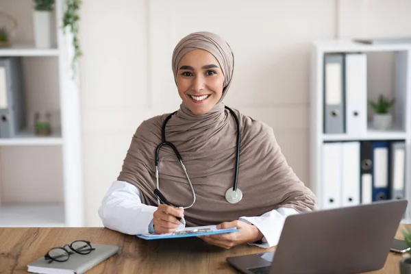 Femme souriante médecin dans le hijab prendre des anamnèse à la clinique — Photo