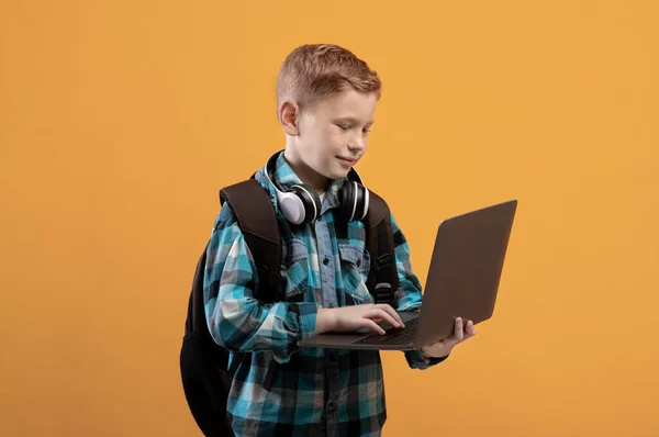 Smart schooljongen met rugzak en headset met laptop — Stockfoto