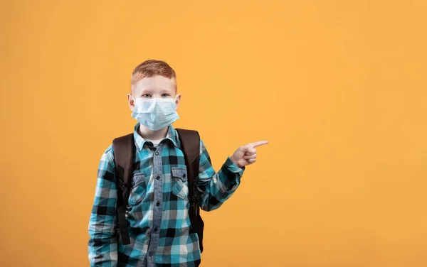 Colegial con mascarilla protectora apuntando al espacio de copia —  Fotos de Stock