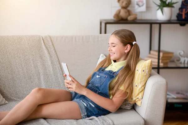 Chica usando su teléfono celular descansando en el sofá — Foto de Stock