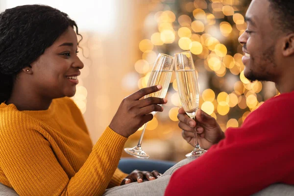 Leende ung afrikansk amerikansk par clink glasögon med champagne i vardagsrummet — Stockfoto