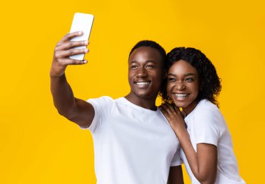 Neşeli Afrikalı Amerikalı çift cep telefonuyla selfie çekiyor.