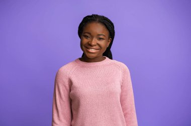 Pembe kazaklı, gülümseyen Afro-Amerikan Kadın Mor Arkaplan Üzerine Pozlar Veriyor